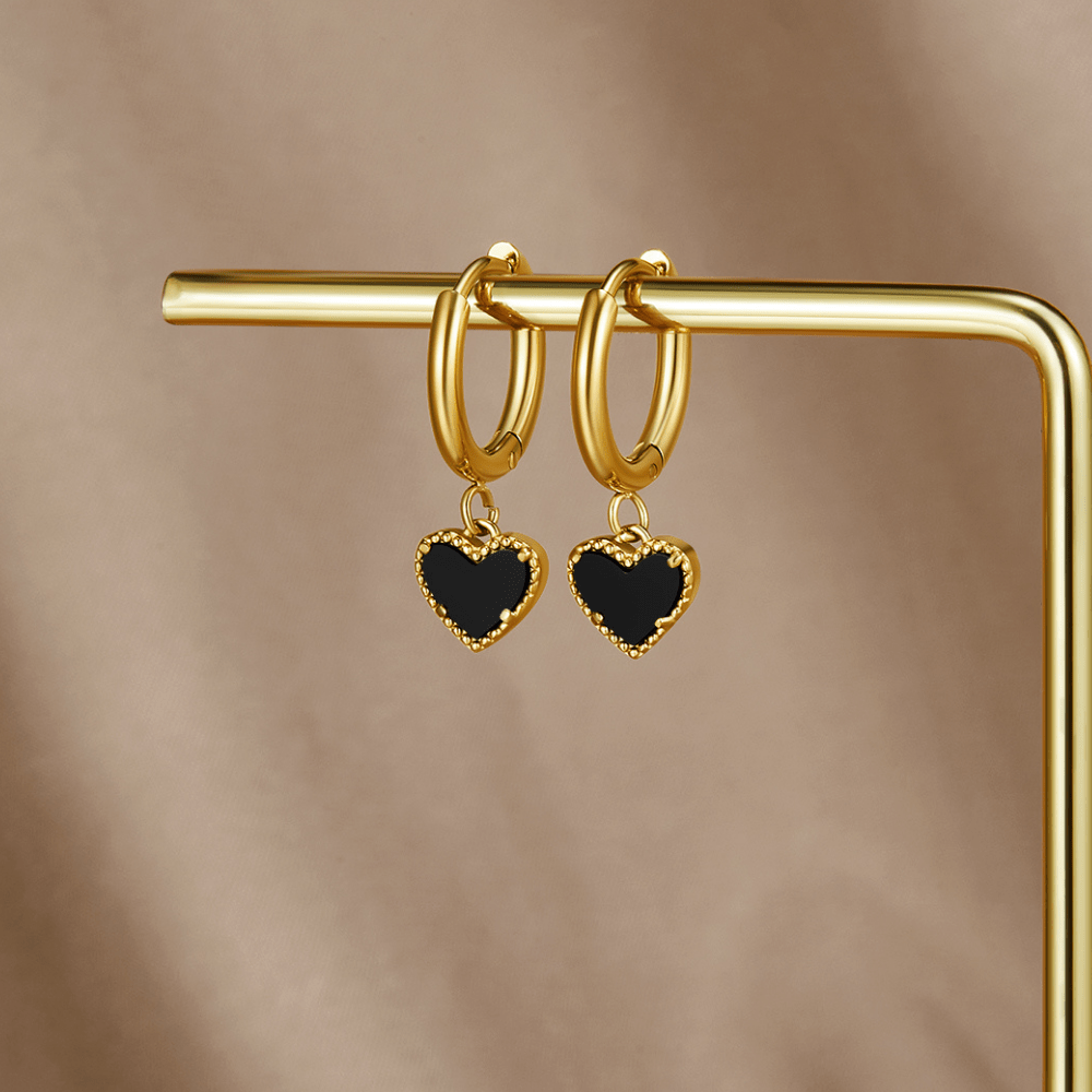 'Tainted Hearts' Hoop Earrings, hanging on a gold display bar, black heart charms