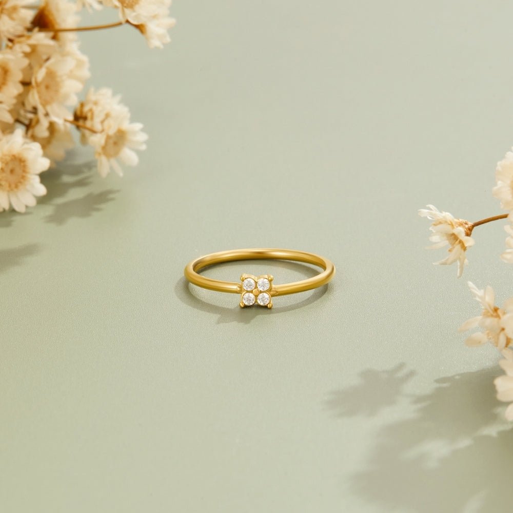 Tiny Petal Gold Ring, standing alone on sage green, beside dried white flowers