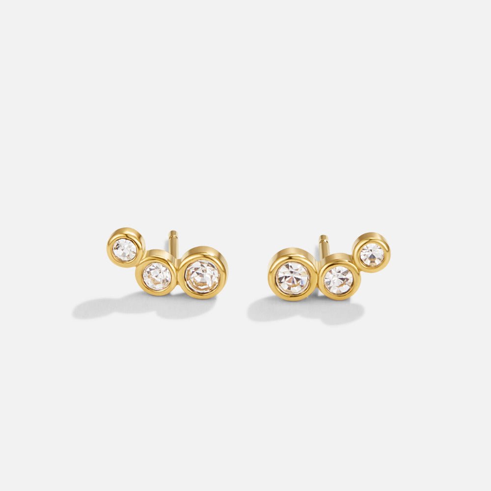 Trio Crystal Stud Earrings, pair of gold stud earrings with three clear stones each, on white