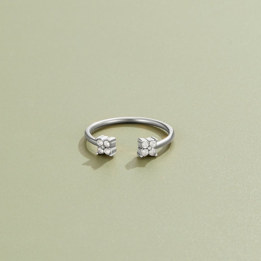 Twin Petal Silver Ring, open silver band with a flower cluster of stones at each end, on sage green