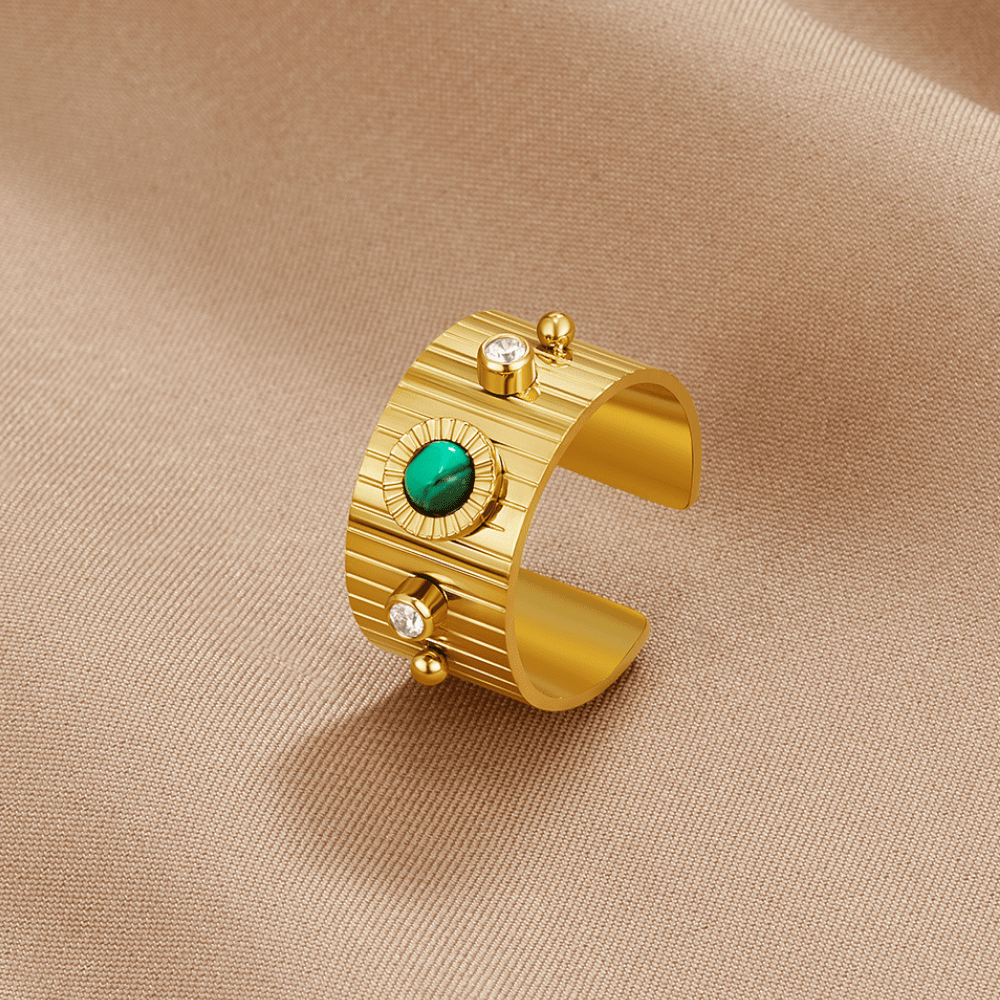 Vintage Dakota Gold Ring, wide open gold band on beige fabric, with a green stone centre