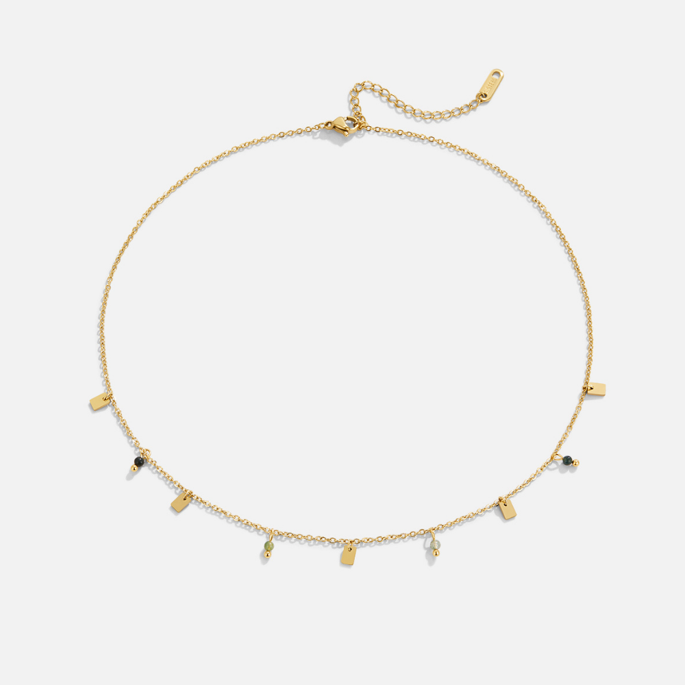 Tara Gold Square Droplet Necklace, laid flat on white, gold chain with small tags and green beads