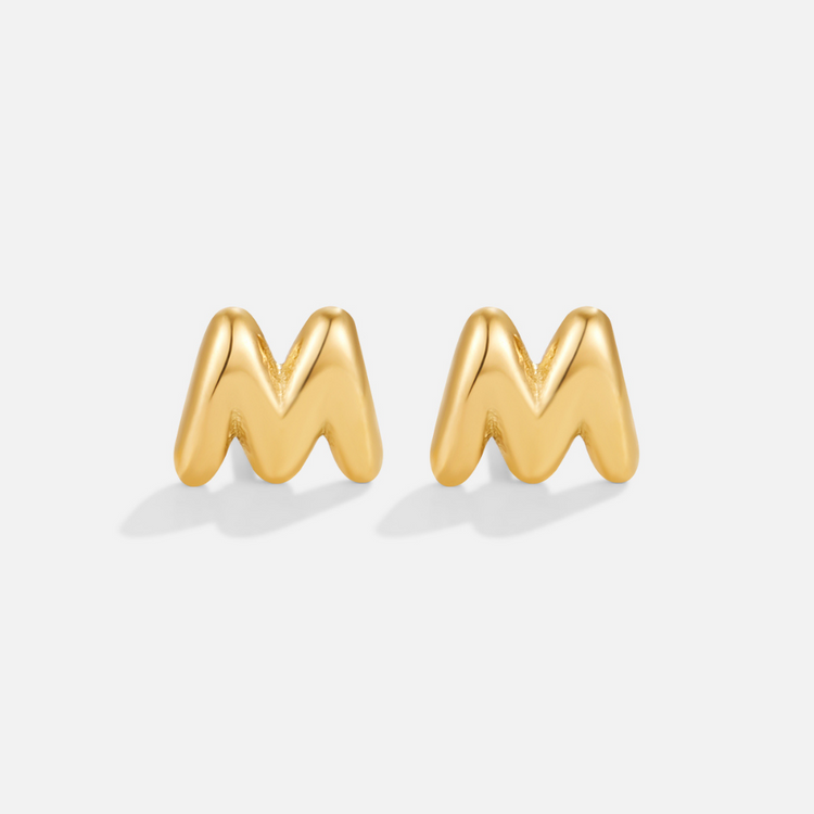Gold Bubble Letter Earrings, pair of puffy gold letter M studs on a plain light grey background