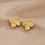 18K Gold Flower Earrings, a pair of four-petal gold earrings lying on beige satin fabric