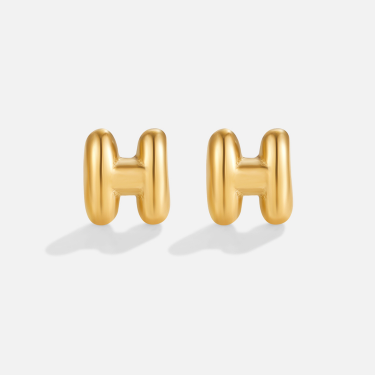Gold Bubble Letter Earrings, a pair of puffy gold letter H earrings on a plain light background