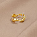18K Gold Wave Ring, open wavy gold ring lying on a beige satin fabric