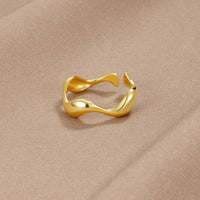 18K Gold Wave Ring, open wavy gold ring lying on a beige satin fabric