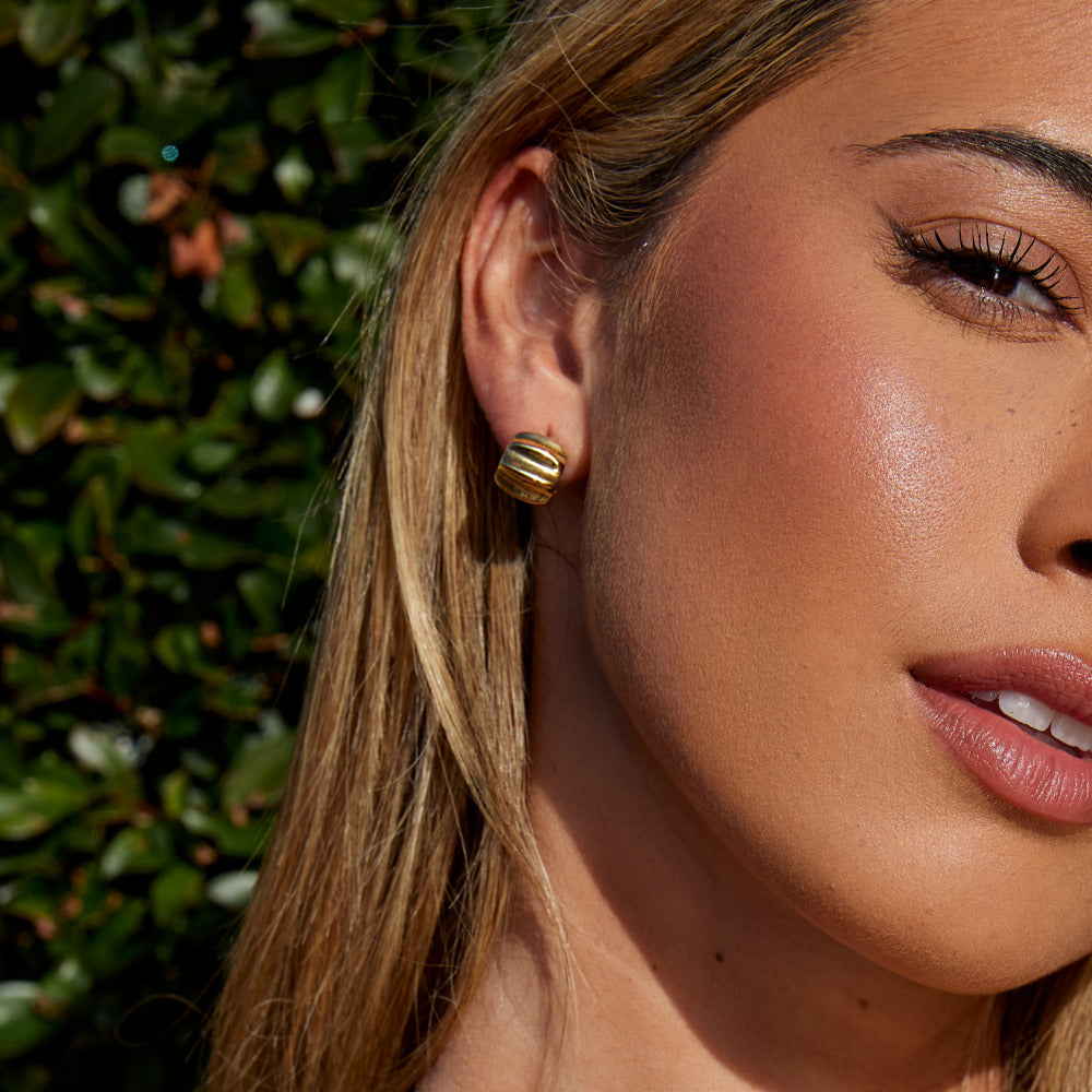 Elsa Mini Wave Hoop Earrings, worn on an ear, close-up of a woman's face, gold ridged hoop
