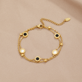 Onyx & White Stone Bracelet, laid flat on beige fabric, gold double chain with black and white