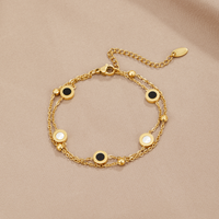 Onyx & White Stone Bracelet, laid flat on beige fabric, gold double chain with black and white