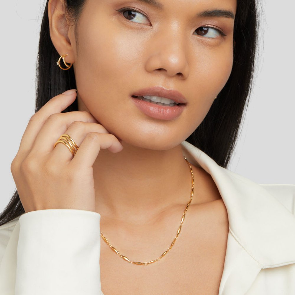 Alea Chain Necklace, worn on a model in a white blazer, with matching gold earring and ring