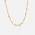Alea Chain Necklace, gold chain necklace laid in a loose curve on white, with its shadow