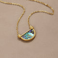 Amalfi Turquoise Shell Necklace, laid flat on a taupe fabric, gold chain with half-moon shell