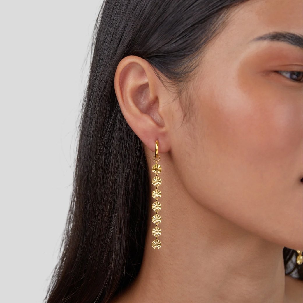 Amari 18K Gold Disc Earrings, worn on an ear, long drop of gold discs with starburst texture