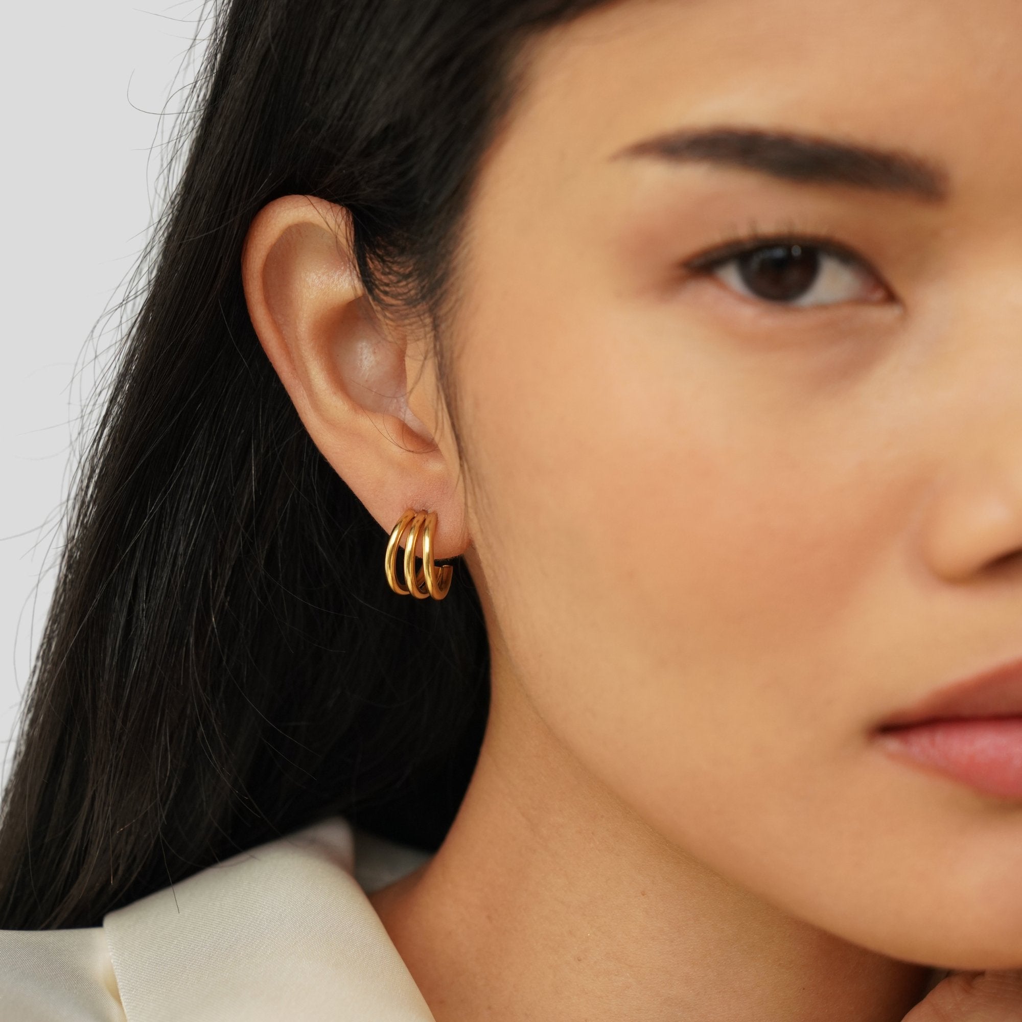 Anaya Triple Gold Hoop Earrings, worn on an ear by a model with long dark hair