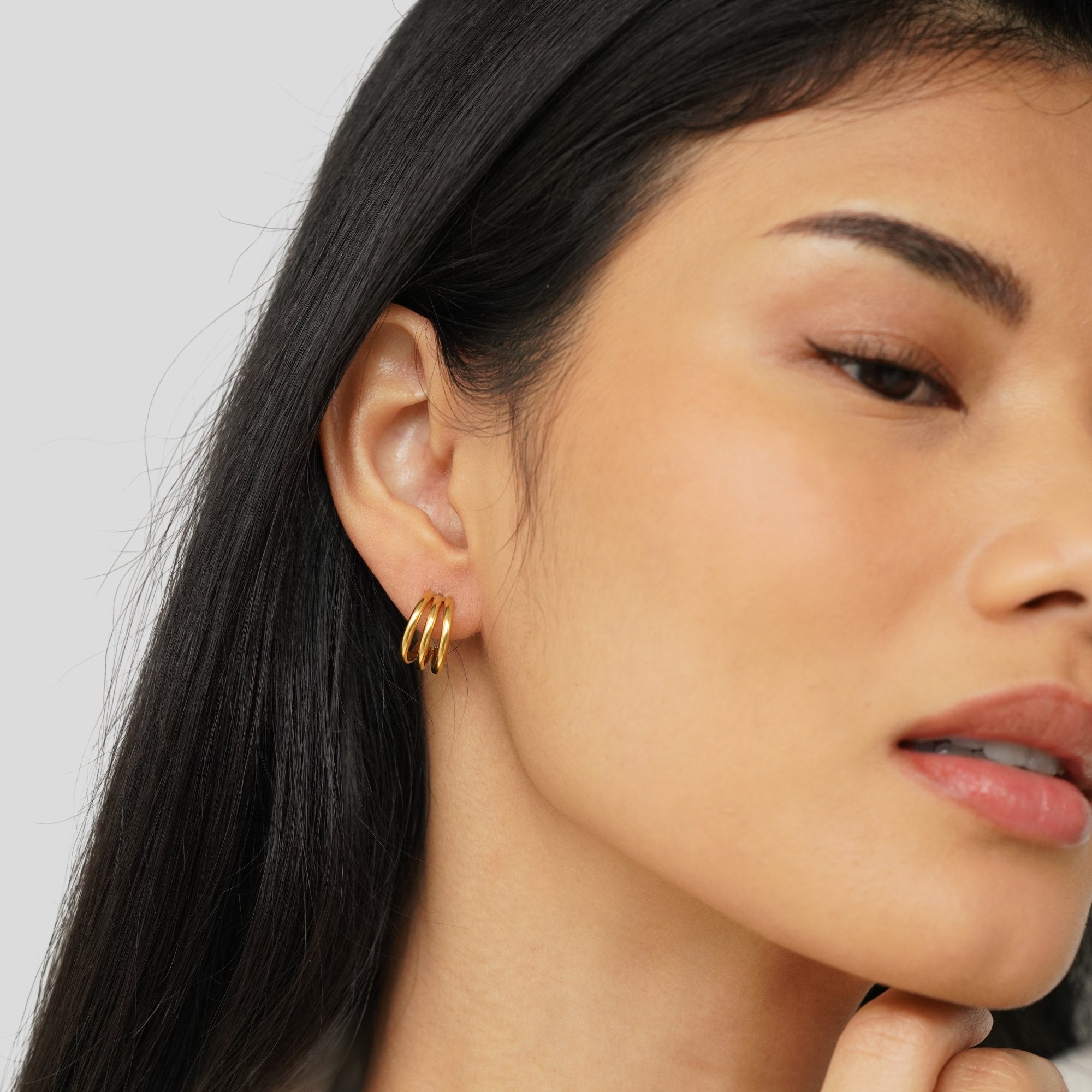 Anaya Triple Gold Hoop Earrings, worn on an ear by a model with long dark hair