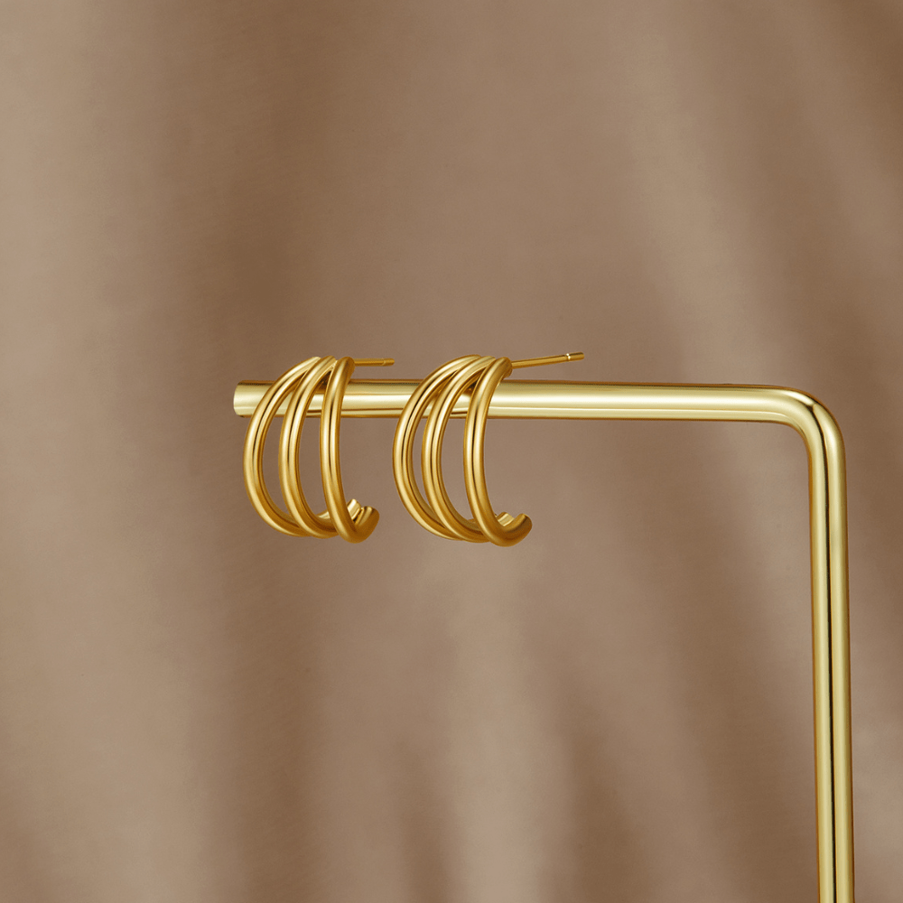 Anaya Triple Gold Hoop Earrings, pair of gold triple-hoop earrings on a gold display stand