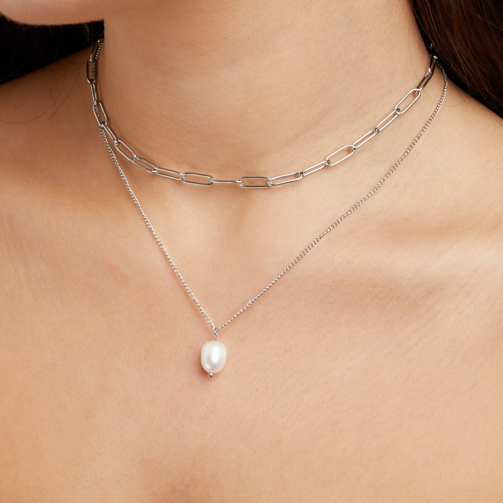 Angela Pearl Silver Necklace, worn on a neck layered with a chunky chain, pearl pendant