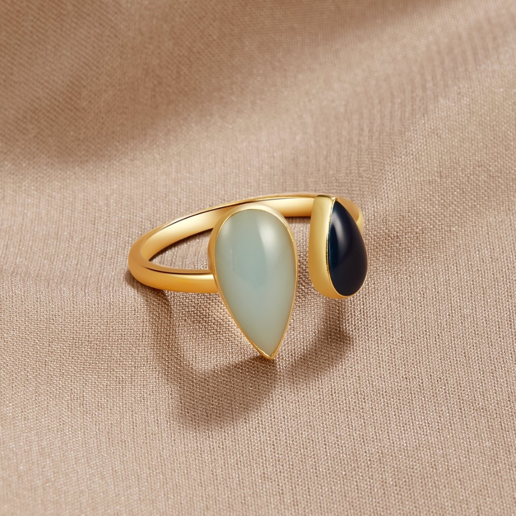 Aquamarine Teardrop Ring, gold ring with pale green and black teardrop stones on beige fabric