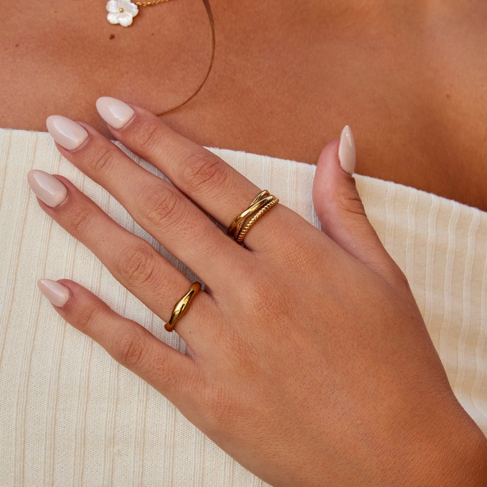 Ara Twisted Crossed Ring, worn on a hand over a cream ribbed top, with gold rings on two fingers
