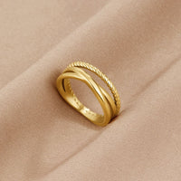 Ara Twisted Crossed Ring, lying on beige satin, gold crossed band with twisted rope edge