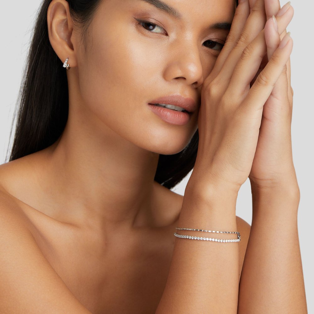 Arelia Crystal Silver Bracelet, worn on a wrist with hands pressed together, silver crystal line