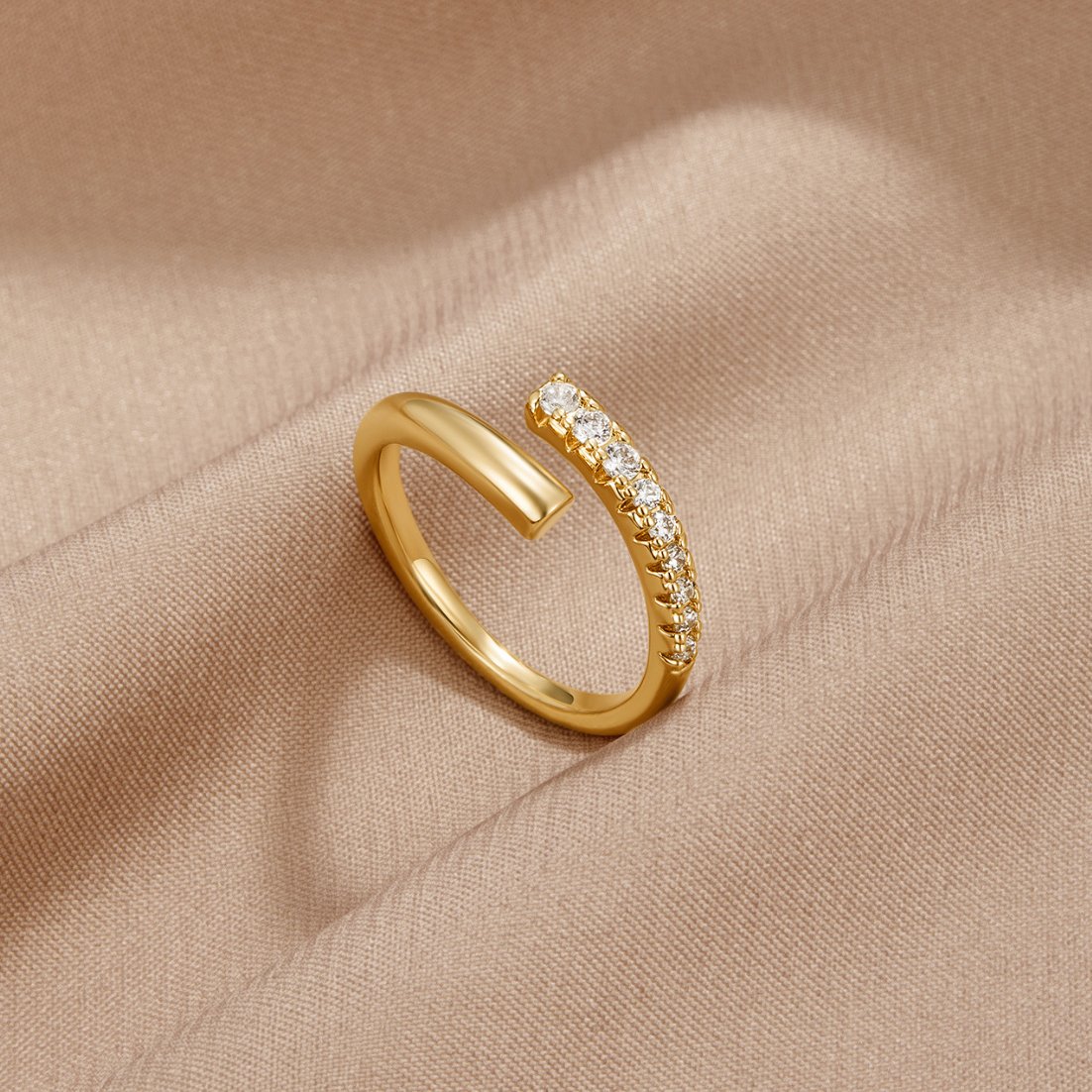 Arya Gold & Crystal Wrap Ring, lying on beige satin, open wrap band with crystal row