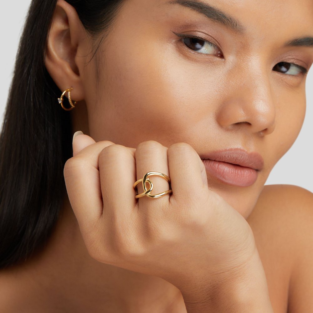 Astrid Gold Ring, worn on a hand with a gold hoop earring visible