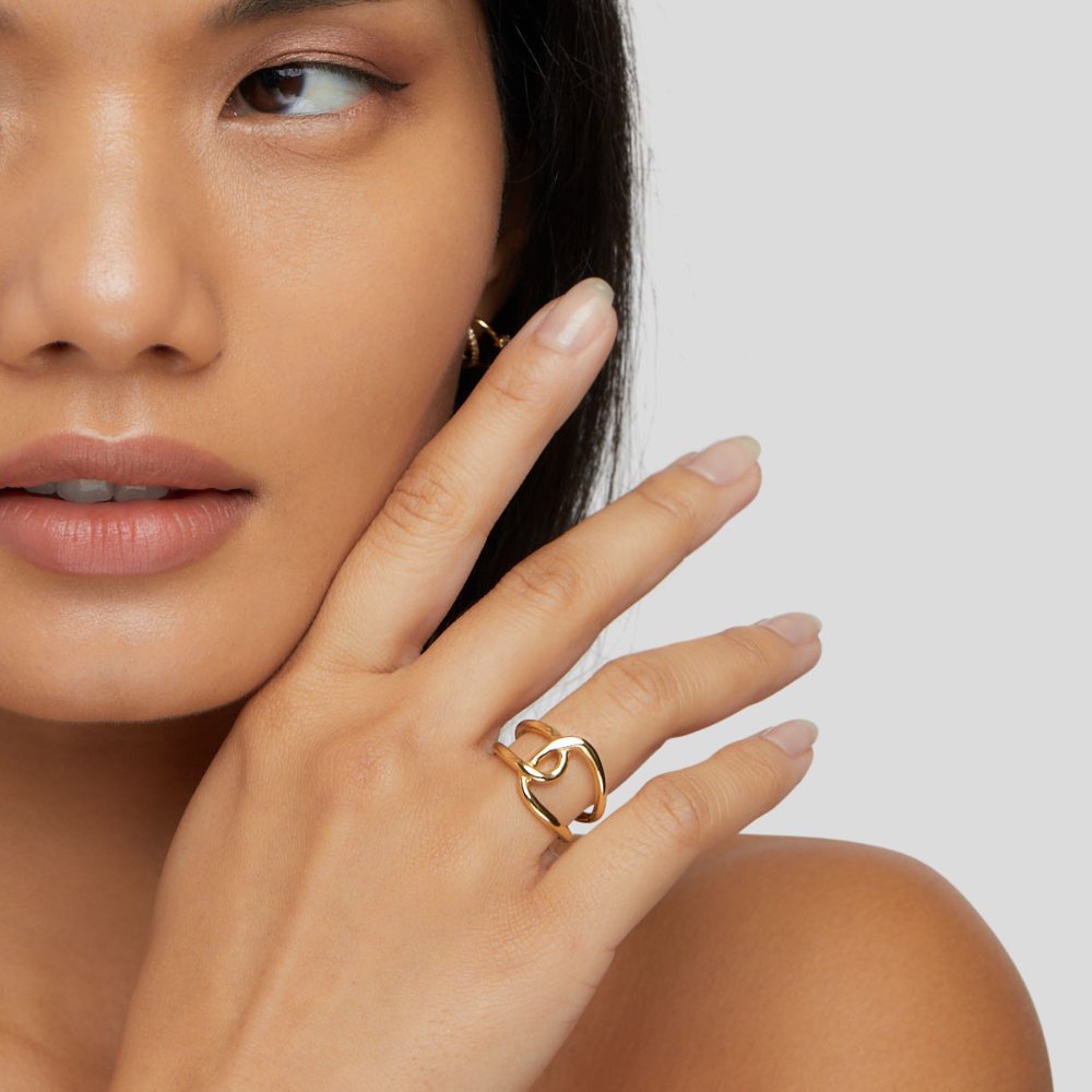 Astrid Gold Ring, worn on a hand near a face, with a gold hoop earring