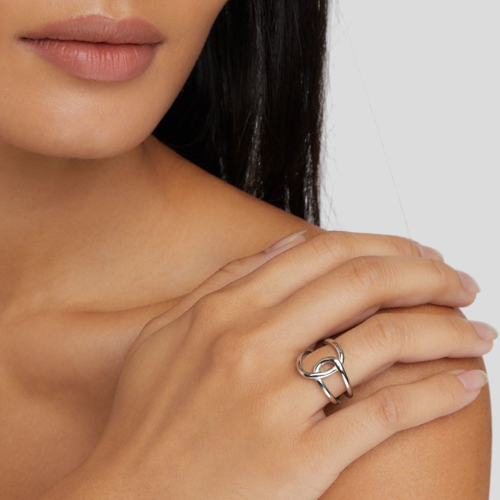 Astrid Silver Ring, worn on a hand resting on a bare shoulder, interlaced silver bands