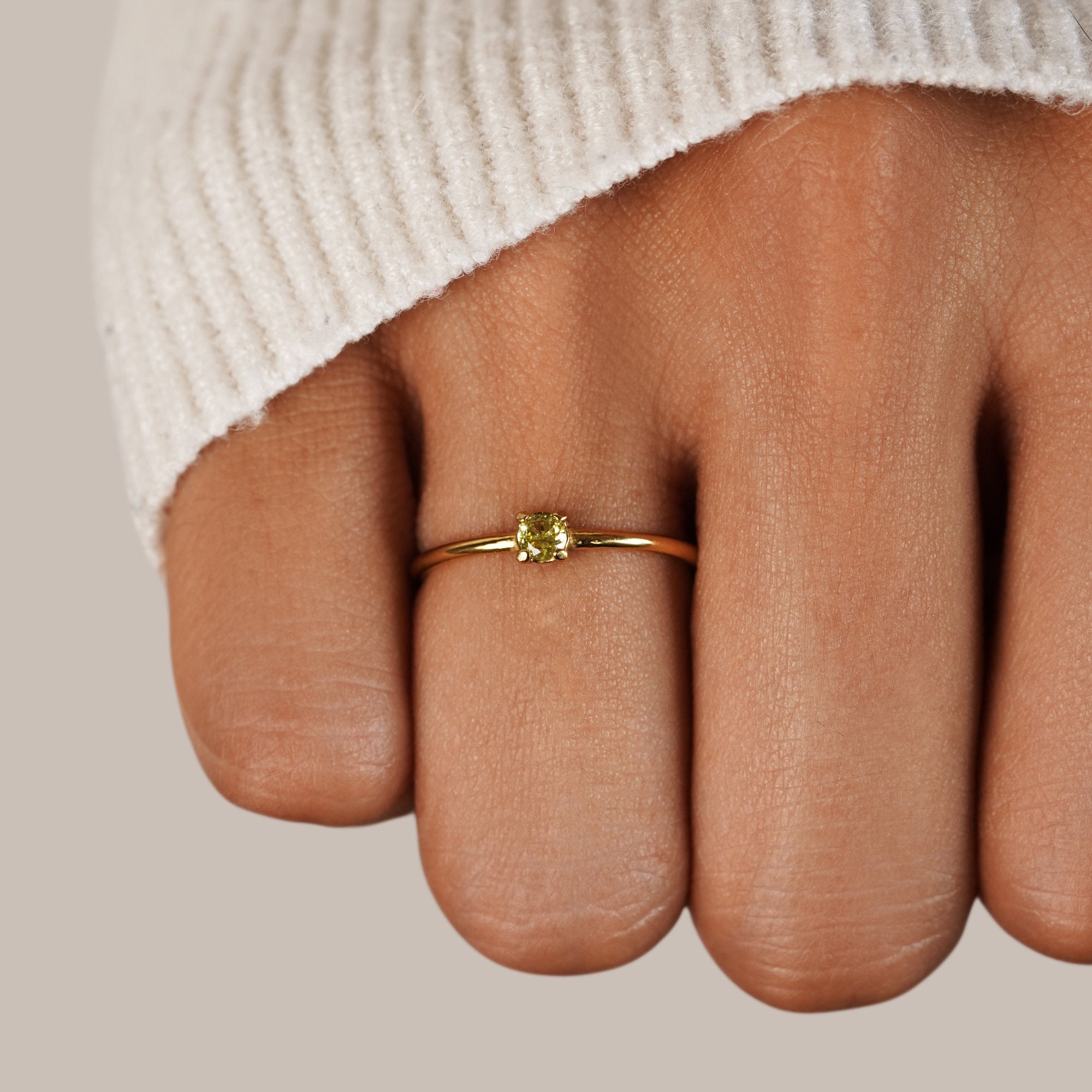 Birthstone 18K Gold Rings, worn on a finger with a cream knit sleeve, yellow stone