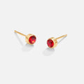 Birthstone Stud Earrings, a pair of gold stud earrings with red faceted stones on a plain background