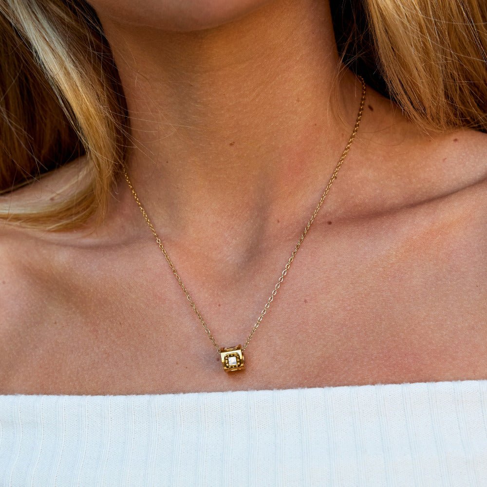 Black Agate Cube Pendant Necklace, worn on a neck with a white top, small gold cube pendant