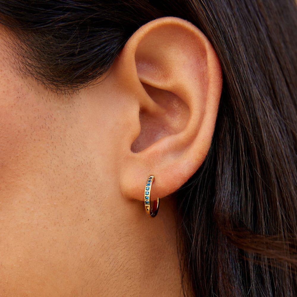 Blue Eternity Hoop Earrings, worn in an ear with blue stones along the gold hoop