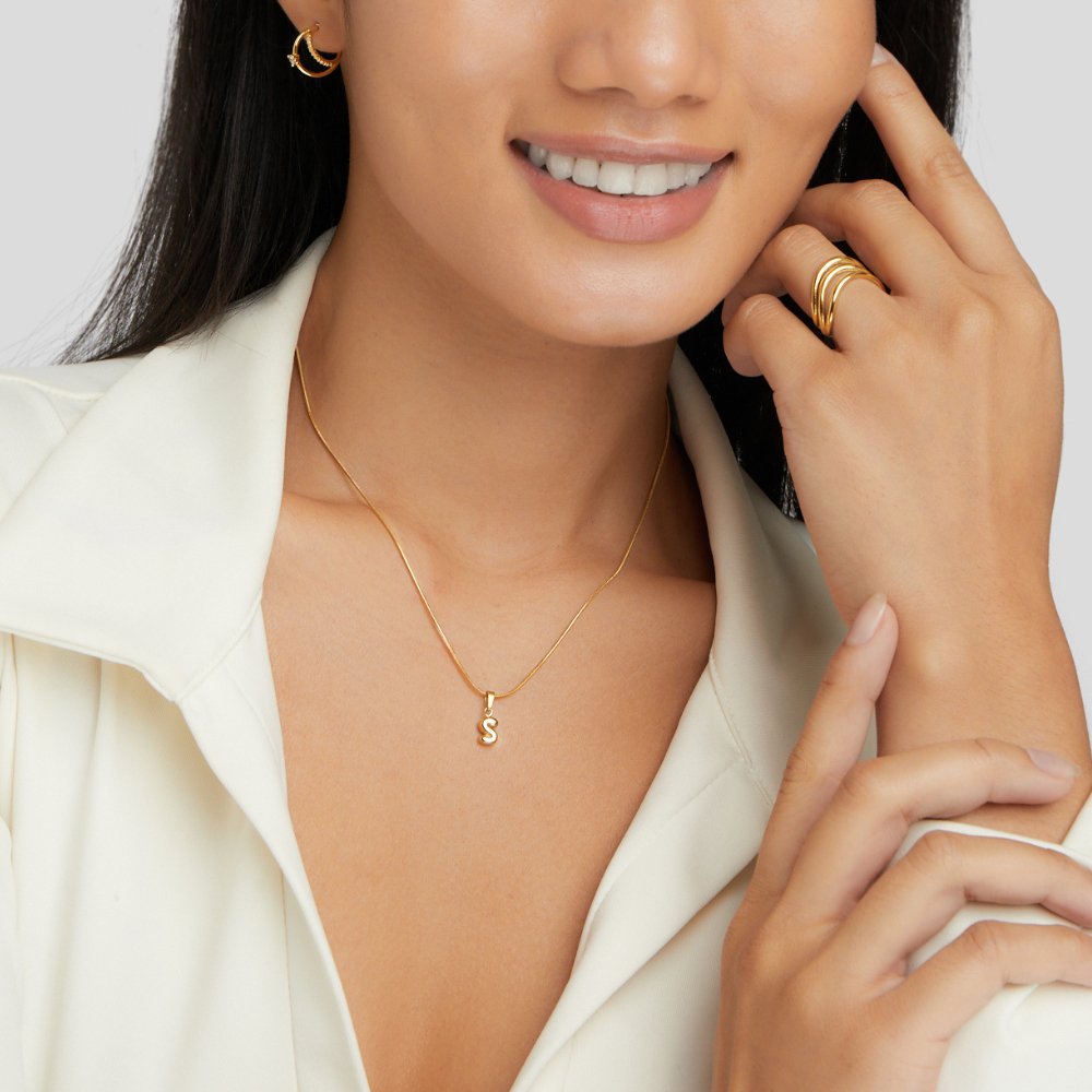 Bubble Letter Necklace, worn on a smiling model in a white collared top