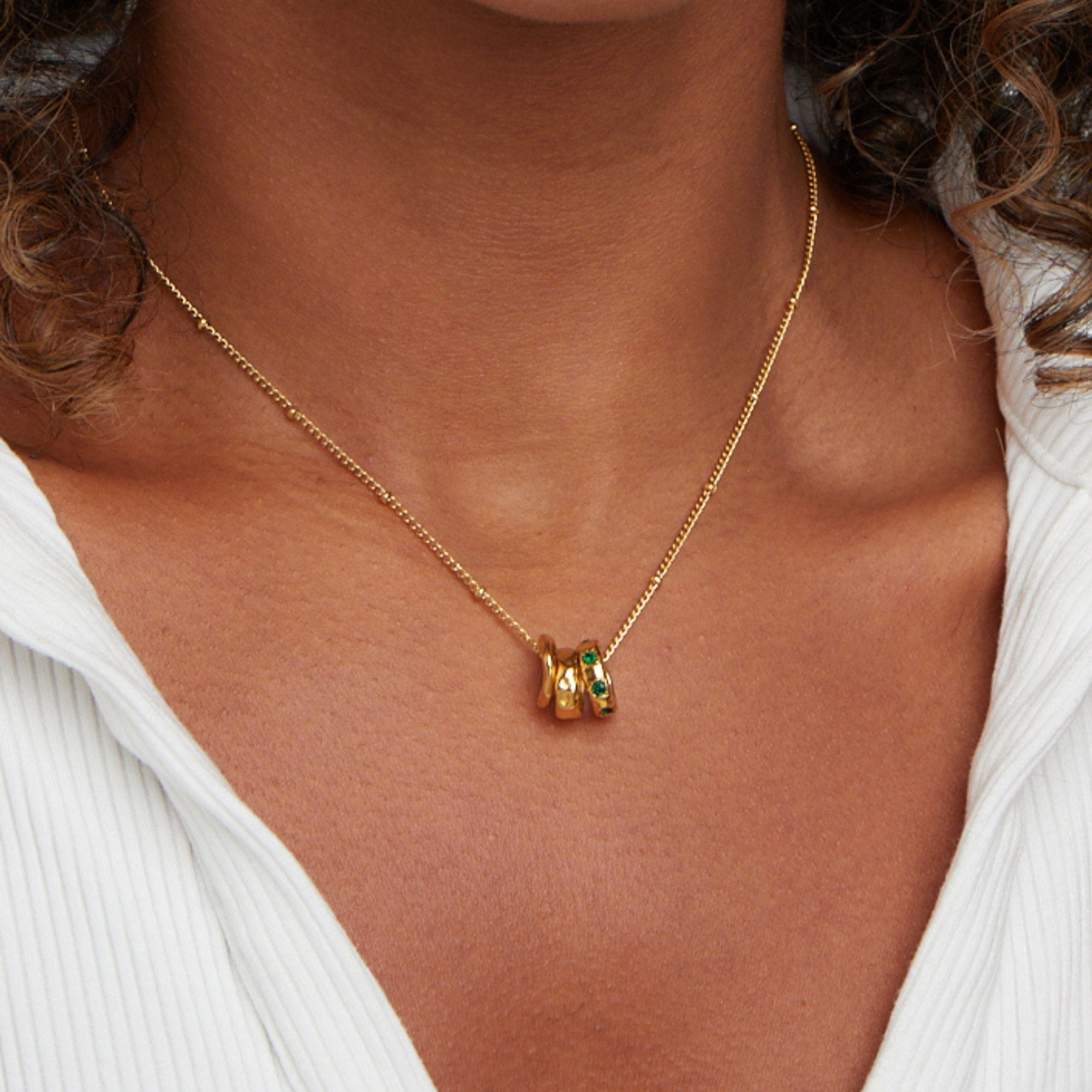 Camilla Pendant Necklace, worn at the neck over a white ribbed top, gold with green stones