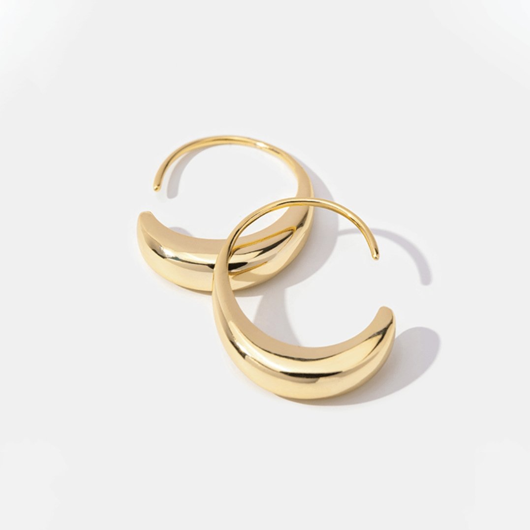 Classic Drop Hoop Earrings, two polished gold hoop earrings lying flat on white