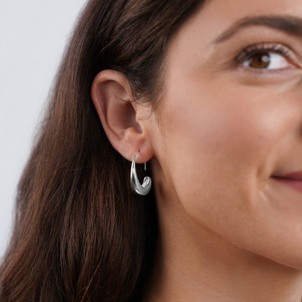 Classic Silver Drop Hoop Earrings, worn on an ear, close-up of a polished silver hoop