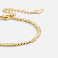 Cordelia Gold Tennis Bracelet, close-up of a gold tennis bracelet curving across white background