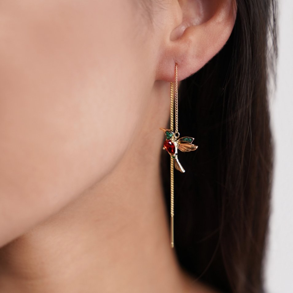 Crystal Hummingbird Tassel Earrings, worn on an ear with a red stone and green-tipped gold wings