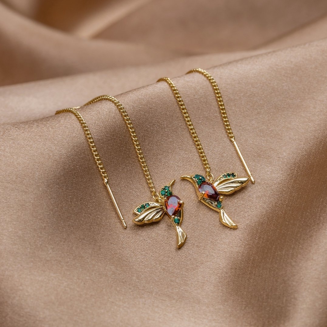 Crystal Hummingbird Tassel Earrings, a pair of gold hummingbird earrings with red stones on satin