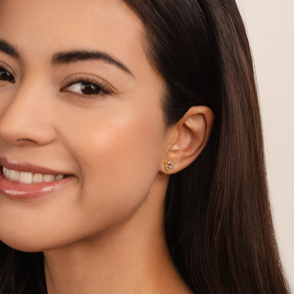 Crystal Leaf Stud Earrings, worn on an ear of a smiling model with long dark hair