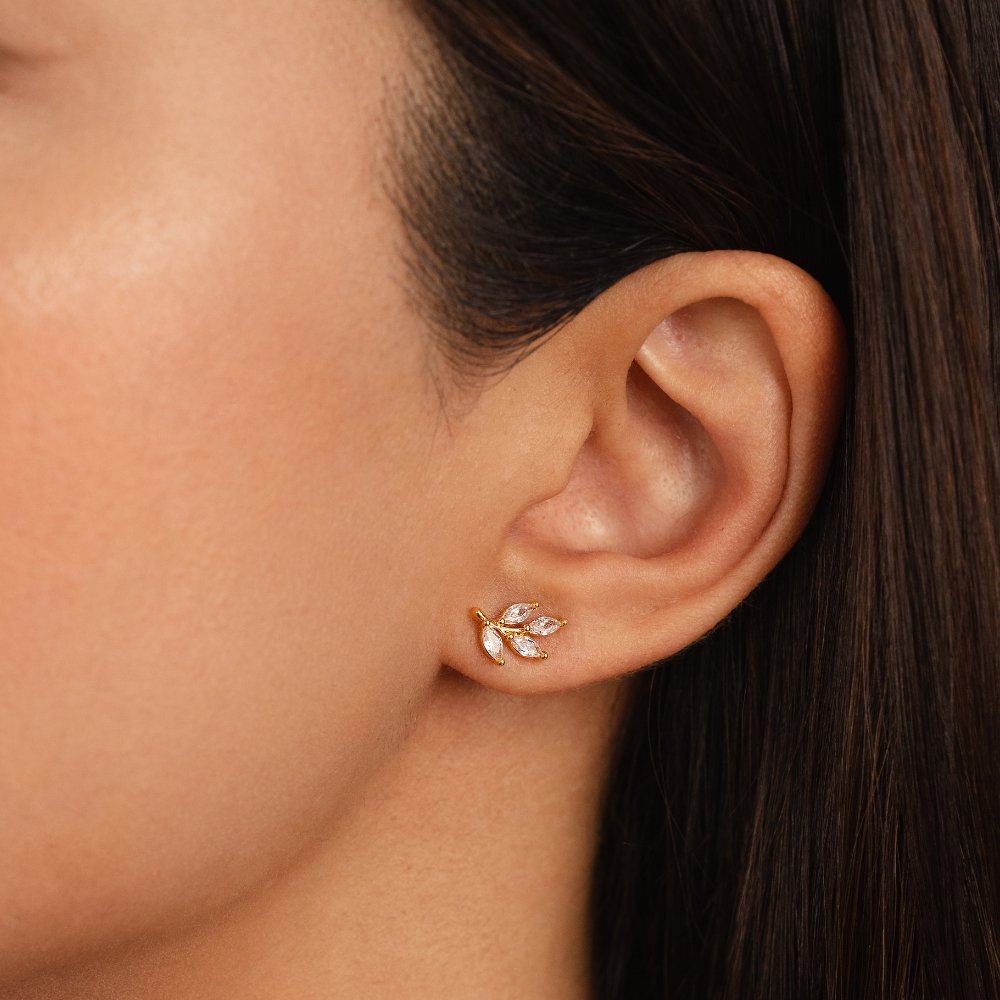 Crystal Leaf Stud Earrings, worn on an ear, close-up with gold leaf stud and clear stones