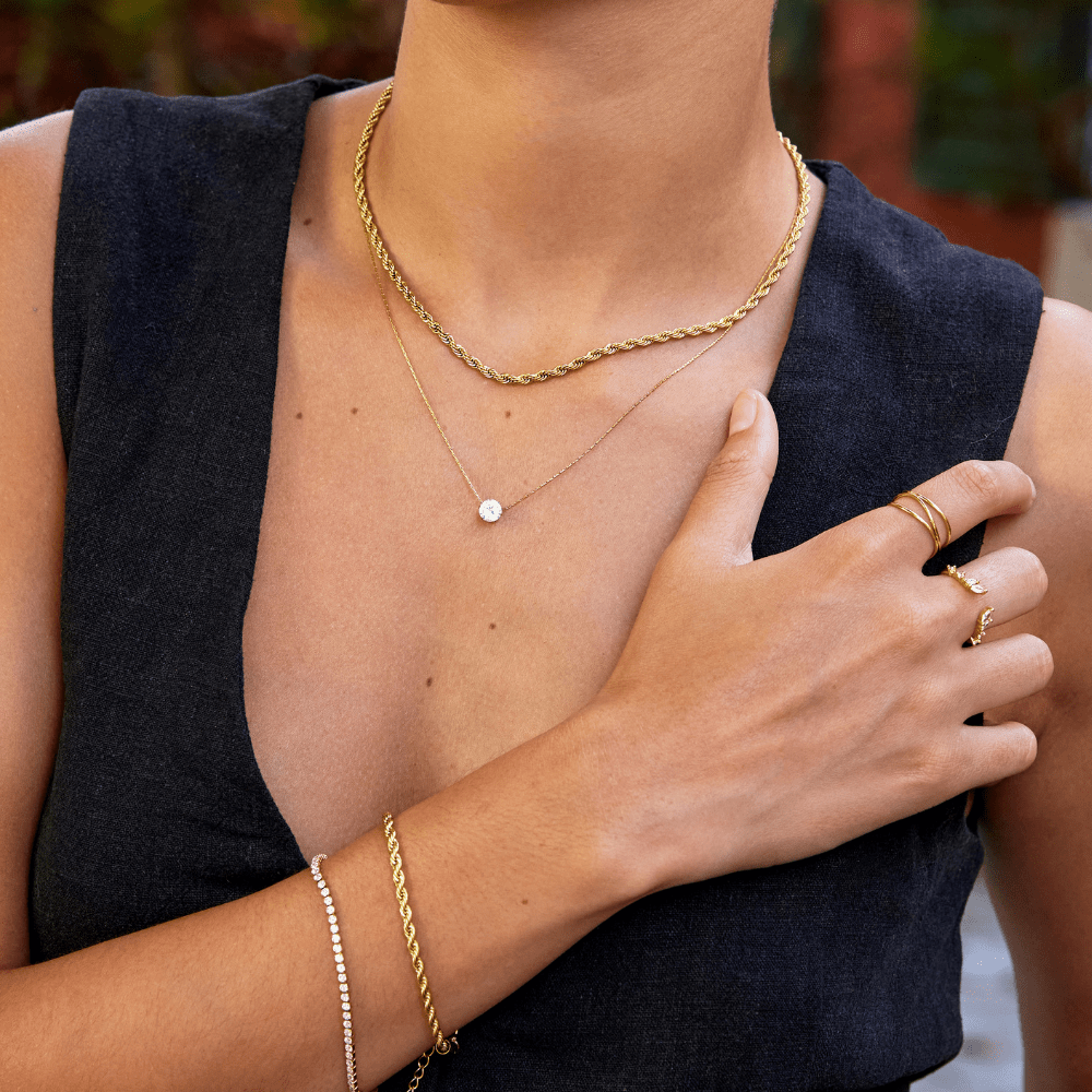 Dainty Round Crystal Necklace, worn layered over a gold rope chain on a model in a dark