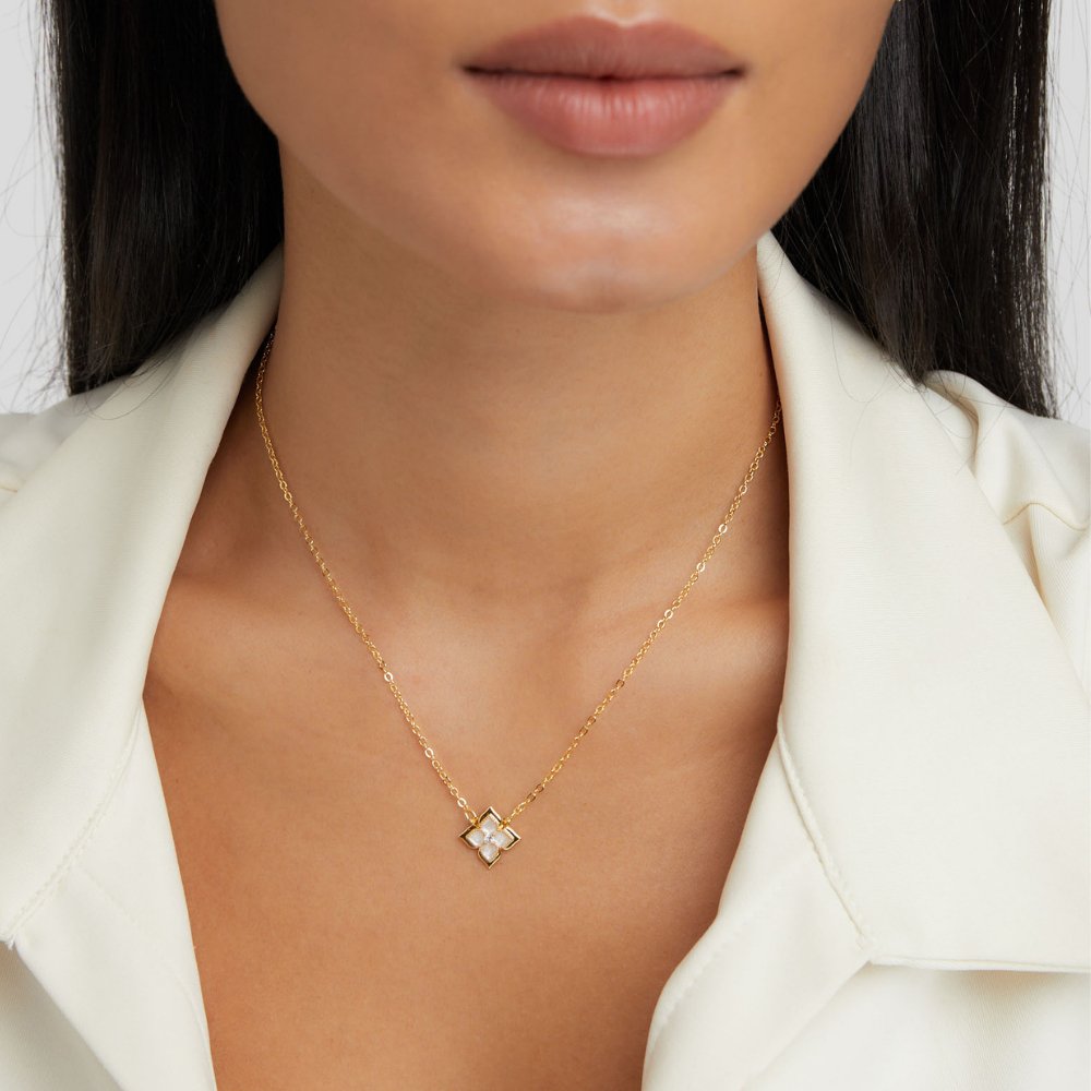 Dalia White Iris Clover Necklace, worn on a neck with a white collared top, gold clover pendant