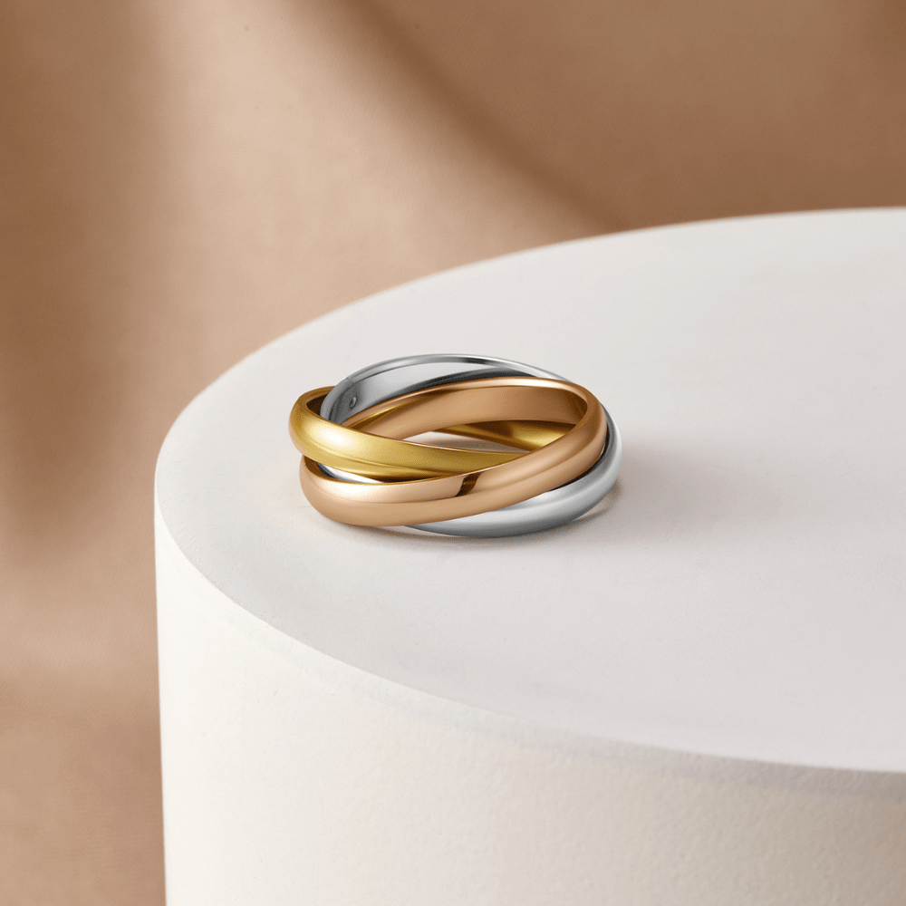 Elena Three-Toned Loop Ring, three interlinked bands in yellow, rose and silver on a white pedestal