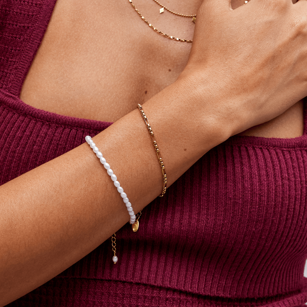 Eli 18K Gold Bracelet, worn on a wrist with a pearl bracelet and gold chain layered