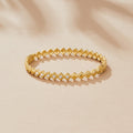 Elle Crystal Marquise Bangle, gold bangle lying flat on a beige surface, with clear stones