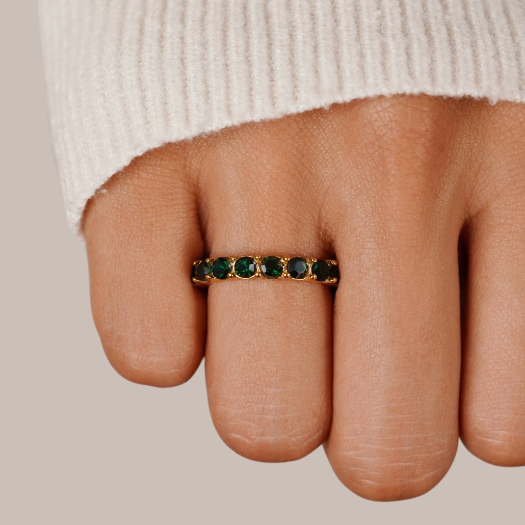 Emerald Beauty 18K Crystal Ring, worn on a hand with a cream knit sleeve, green stones