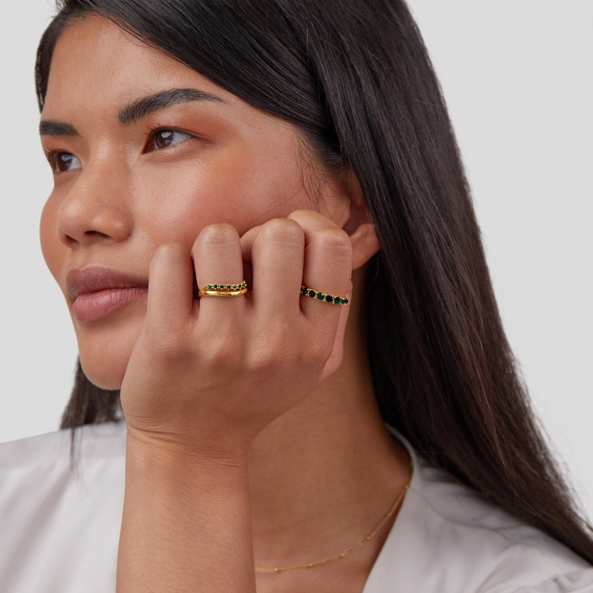Emerald Beauty 18K Crystal Ring, worn on a hand resting against a cheek, with gold rings set